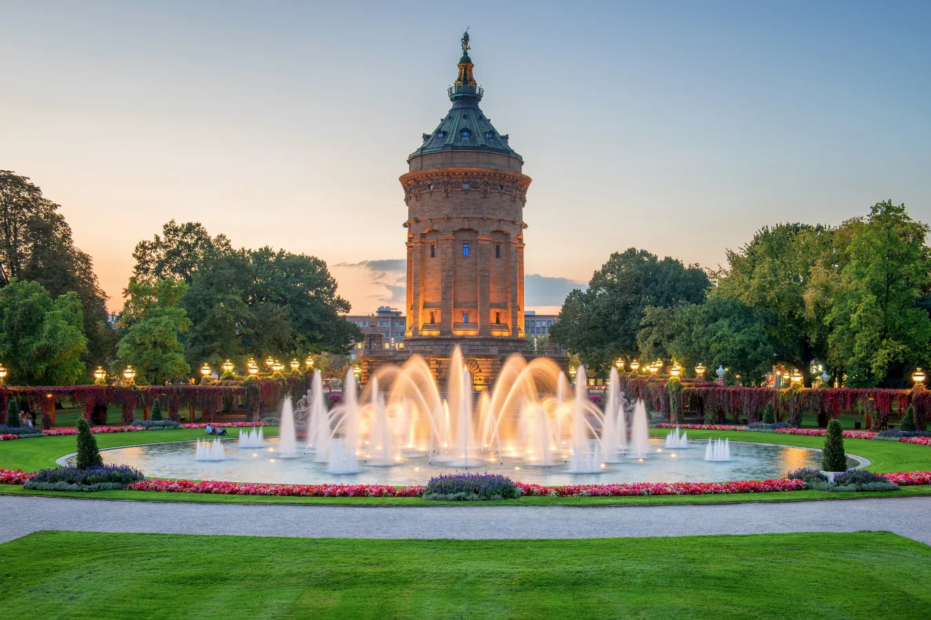Der Mannheimer Wasserturm mit beleuchtetem Springbrunnen in der Abenddämmerung