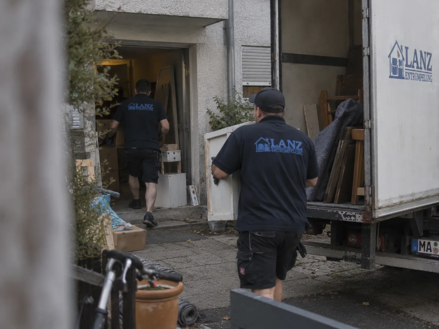 Zwei Mitarbeiter von Lanz Entrümpelung tragen Möbel aus einem Mannheimer Hauseingang